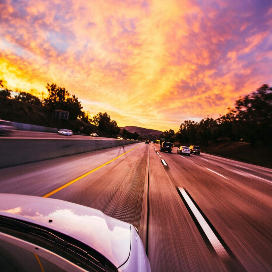 car driving toward sunset